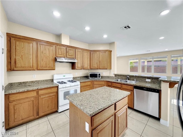 kitchen featuring a kitchen island, light stone countertops, sink, and appliances with stainless steel finishes