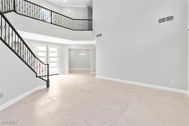 interior space featuring french doors, a towering ceiling, and a notable chandelier