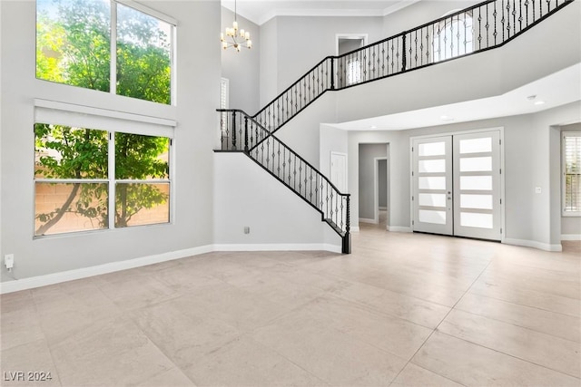 unfurnished living room featuring french doors, crown molding, light tile patterned floors, a notable chandelier, and a high ceiling