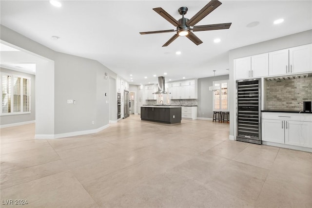 unfurnished living room featuring sink, wine cooler, plenty of natural light, and ceiling fan