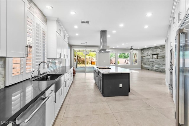 kitchen featuring ceiling fan, sink, a kitchen island, white cabinets, and exhaust hood