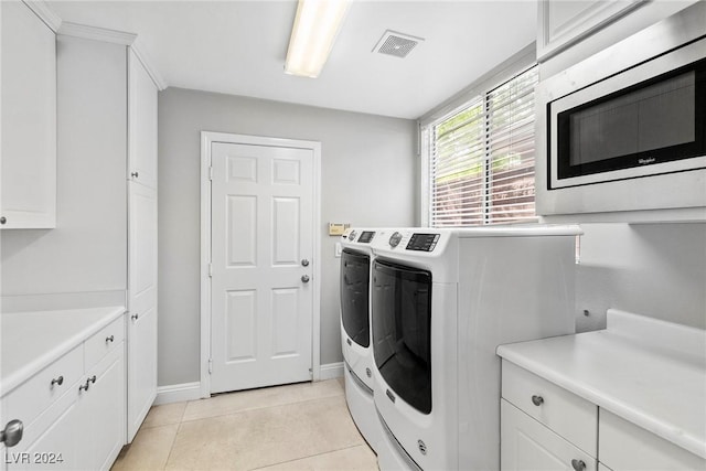 laundry room featuring cabinets, light tile patterned floors, and washing machine and dryer