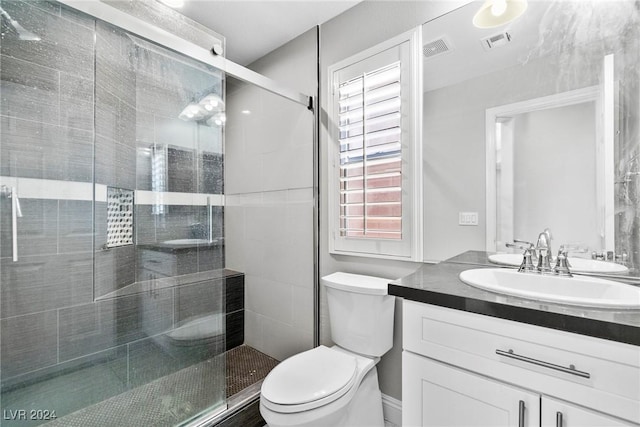 bathroom featuring vanity, toilet, and a shower with door