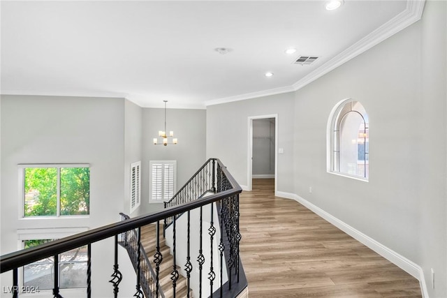 hallway with crown molding, light hardwood / wood-style flooring, and an inviting chandelier