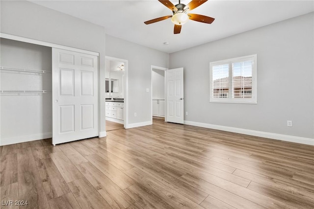 unfurnished bedroom featuring ceiling fan, a closet, light hardwood / wood-style flooring, and ensuite bath