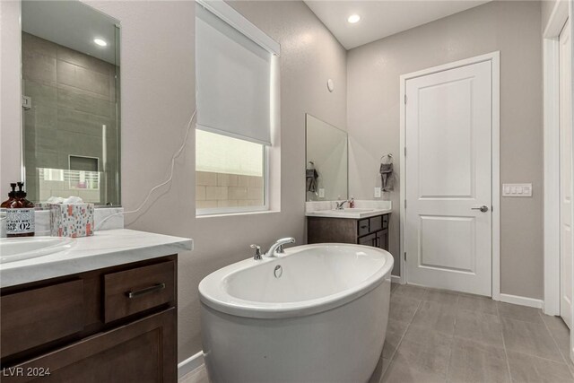 bathroom featuring tile patterned flooring, vanity, and a bath