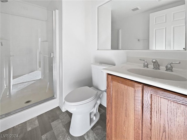 bathroom with vanity, toilet, and a shower with door