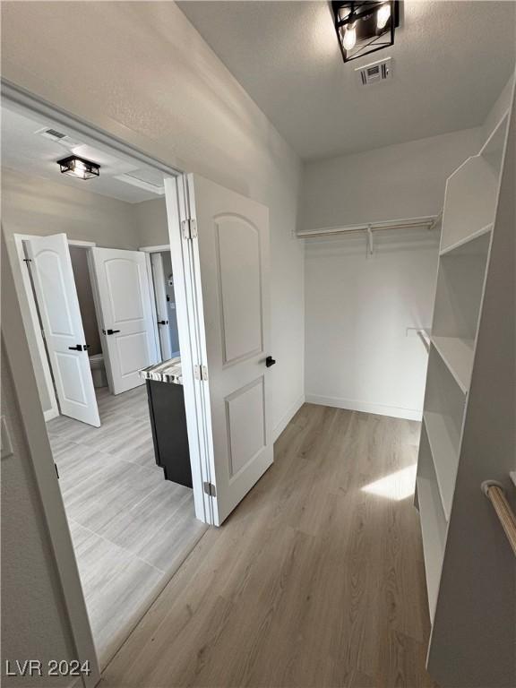 walk in closet with light wood-type flooring