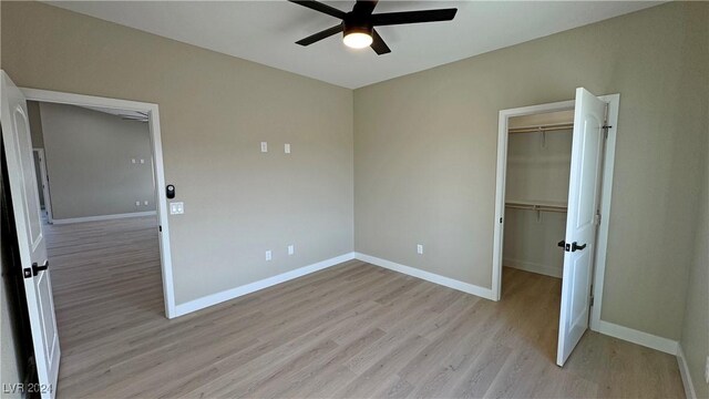 unfurnished bedroom with ceiling fan, light hardwood / wood-style floors, a walk in closet, and a closet