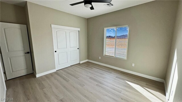 unfurnished bedroom featuring ceiling fan, a closet, and light hardwood / wood-style flooring