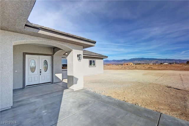 view of exterior entry with a patio area and a mountain view