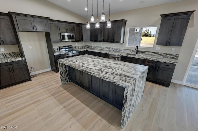 kitchen with light stone countertops, appliances with stainless steel finishes, light wood-type flooring, decorative light fixtures, and a kitchen island