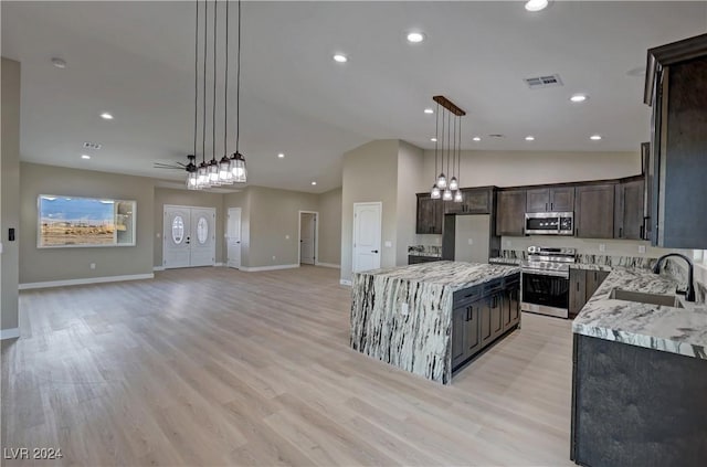 kitchen with appliances with stainless steel finishes, ceiling fan, sink, decorative light fixtures, and a kitchen island