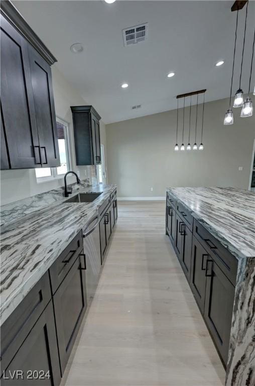 kitchen with light stone countertops, sink, light hardwood / wood-style flooring, dishwasher, and hanging light fixtures