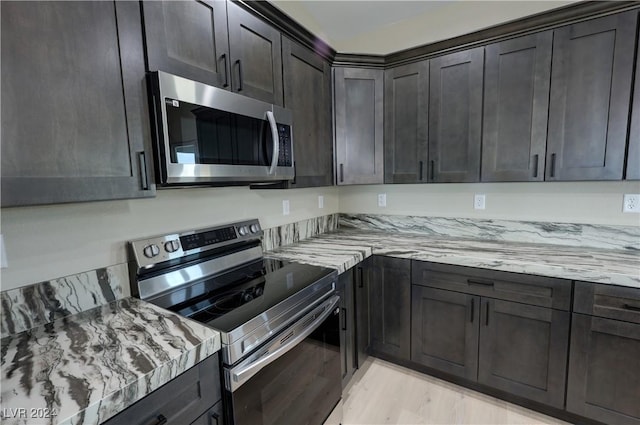 kitchen featuring light stone countertops, appliances with stainless steel finishes, and dark brown cabinets