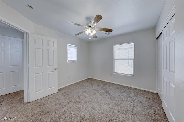 unfurnished bedroom featuring ceiling fan, light carpet, and multiple windows