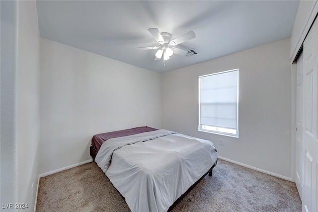 carpeted bedroom featuring ceiling fan and a closet