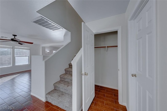 stairway with ceiling fan and wood-type flooring