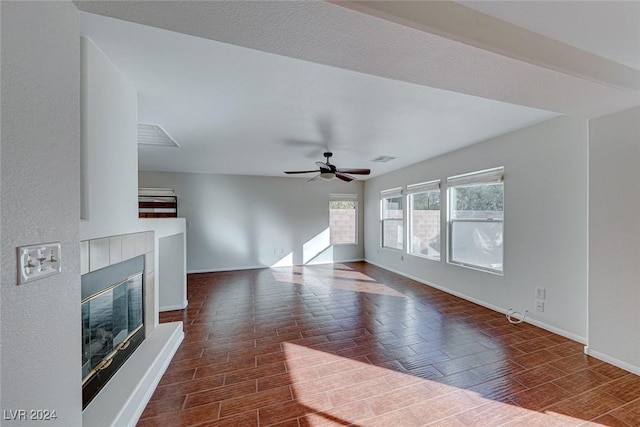 unfurnished living room featuring dark hardwood / wood-style floors, ceiling fan, and a tiled fireplace