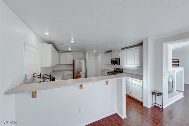 kitchen with a breakfast bar area, kitchen peninsula, white cabinetry, and stainless steel appliances