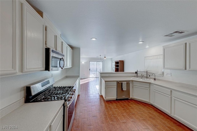 kitchen featuring appliances with stainless steel finishes, a textured ceiling, sink, light hardwood / wood-style flooring, and white cabinets