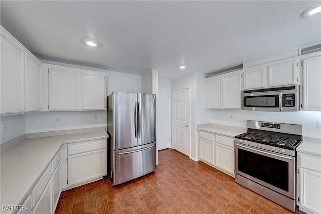 kitchen featuring stainless steel appliances, white cabinetry, and light hardwood / wood-style floors