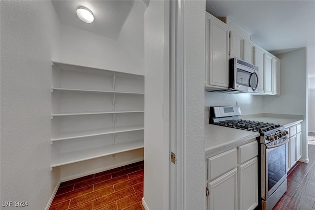 kitchen featuring dark hardwood / wood-style floors, white cabinetry, and stainless steel appliances