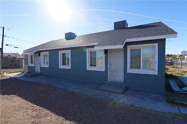 view of front of home with roof with shingles, fence, and stucco siding