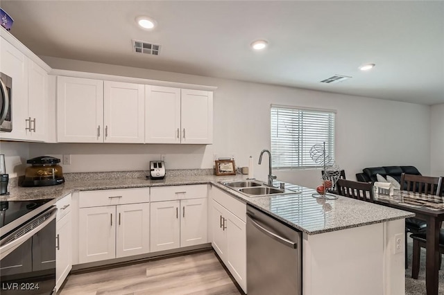 kitchen with kitchen peninsula, stainless steel appliances, sink, light hardwood / wood-style flooring, and white cabinetry