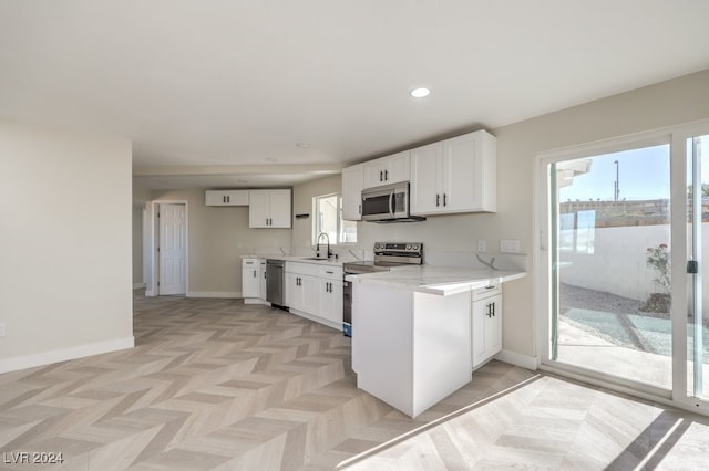 kitchen featuring sink, stainless steel appliances, white cabinets, kitchen peninsula, and light parquet flooring