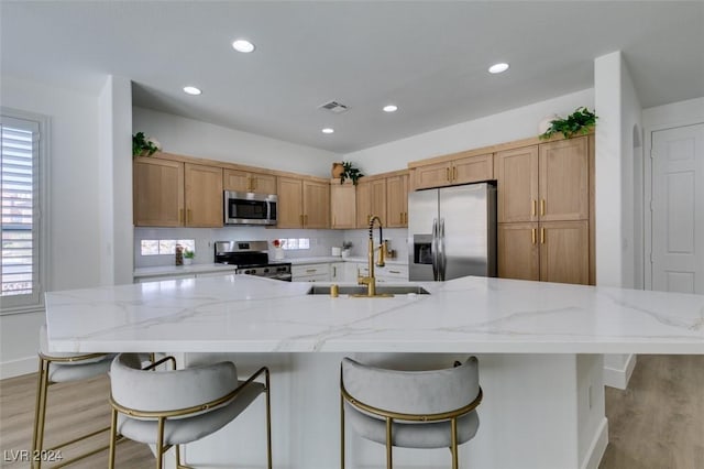 kitchen featuring appliances with stainless steel finishes, light hardwood / wood-style floors, a large island, and sink