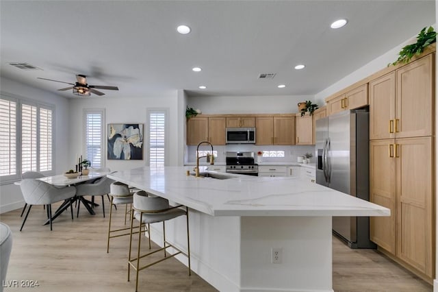 kitchen with a large island, sink, light wood-type flooring, and stainless steel appliances