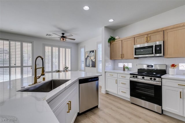 kitchen featuring sink, white cabinetry, stainless steel appliances, and light wood-type flooring