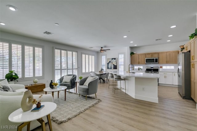 living room featuring ceiling fan, a healthy amount of sunlight, sink, and light hardwood / wood-style flooring