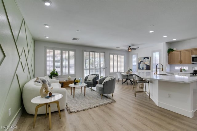 living room with ceiling fan, sink, and light hardwood / wood-style flooring