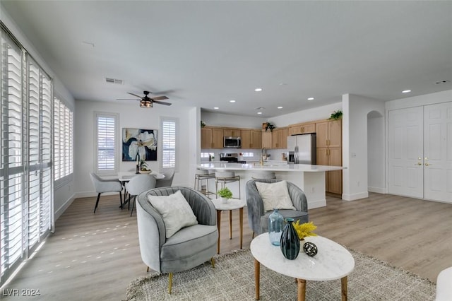 living room featuring light wood-type flooring, ceiling fan, and sink