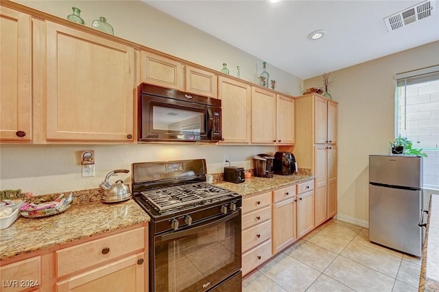 kitchen with light stone counters, light brown cabinets, light tile patterned floors, and black appliances