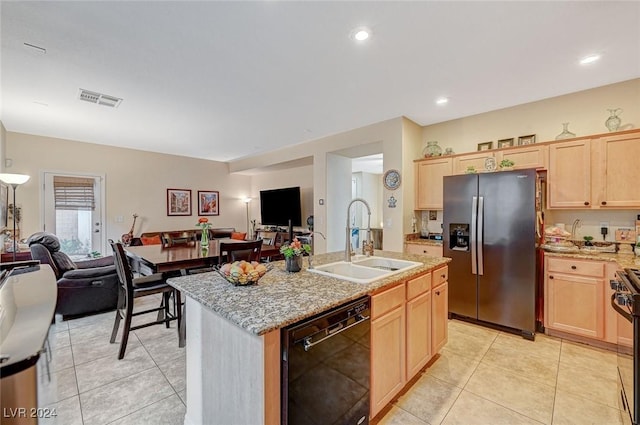 kitchen with sink, stainless steel appliances, light brown cabinetry, and an island with sink