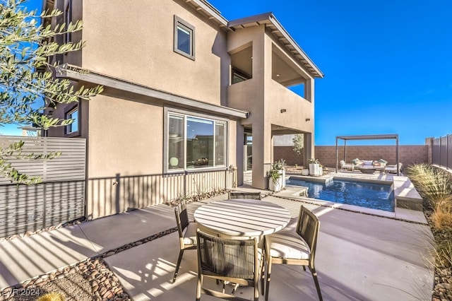 back of property with a patio, a fenced in pool, pool water feature, and a balcony