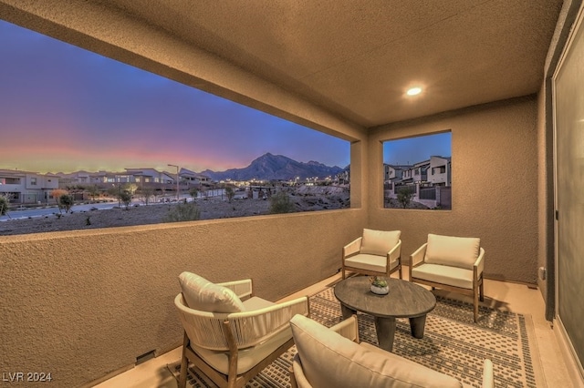 patio terrace at dusk featuring a mountain view and a balcony