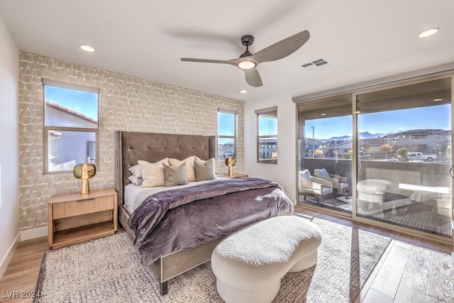 bedroom featuring access to exterior, multiple windows, light hardwood / wood-style floors, and ceiling fan