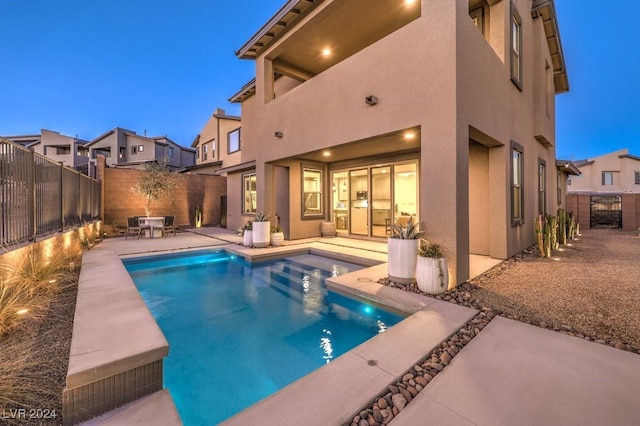 pool at dusk featuring a patio area