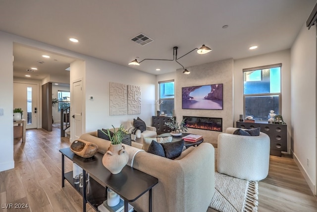 living room with a wealth of natural light, a large fireplace, and light hardwood / wood-style floors