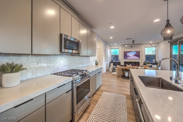 kitchen featuring light stone counters, sink, stainless steel appliances, and light hardwood / wood-style flooring