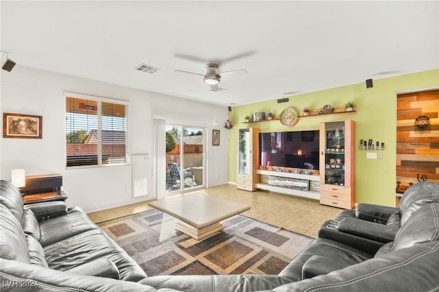 tiled living room featuring ceiling fan and wooden walls