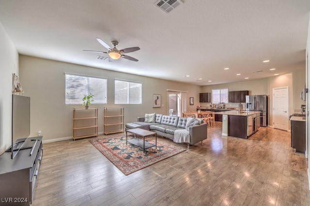 living room with ceiling fan, light wood-type flooring, and sink