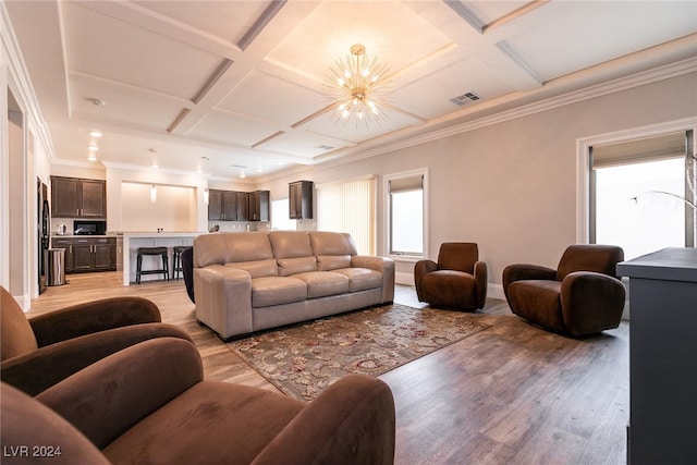 living room featuring coffered ceiling, ornamental molding, beam ceiling, light hardwood / wood-style floors, and a chandelier