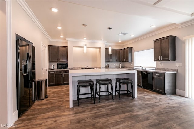 kitchen with decorative light fixtures, dark hardwood / wood-style flooring, a center island with sink, and black appliances