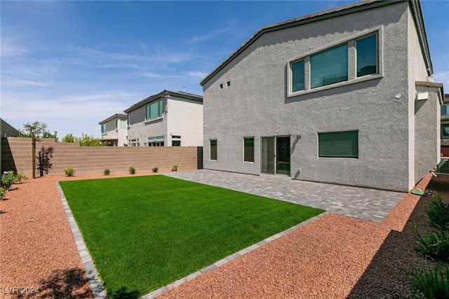 back of house featuring a lawn and a patio