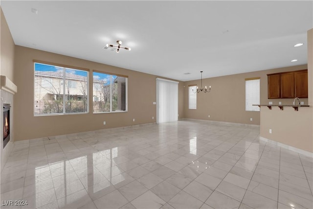 unfurnished living room featuring light tile patterned floors and a chandelier